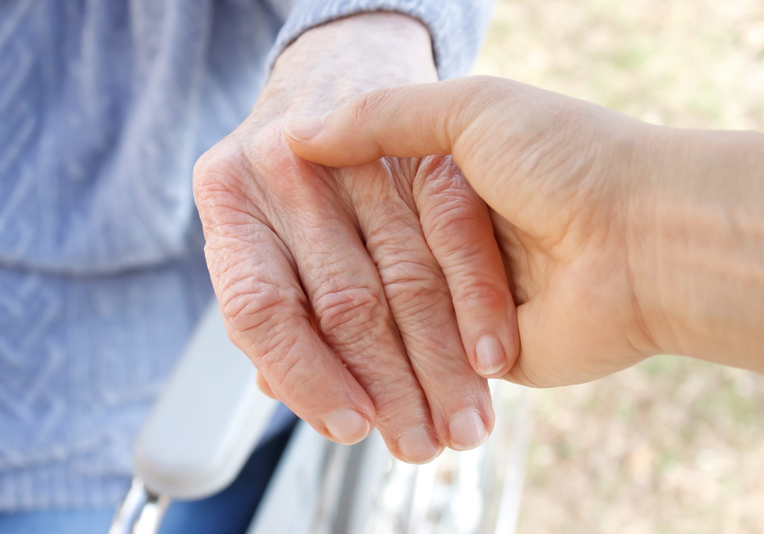 Young woman's hand holding old woman's hand